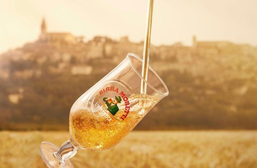 Wine glass with logo being filled, blurred background of hills and sky.